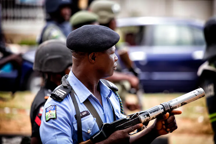 A police officer with a blue shirt and a gun.