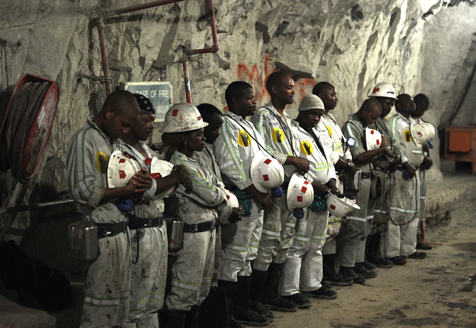 Miners stand in a line, praying.