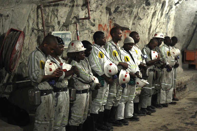Miners stand in a line, praying.