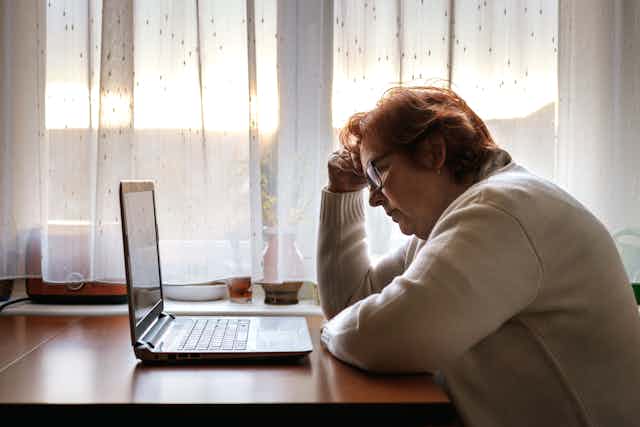 Worried senior woman browsing bad news on laptop.
