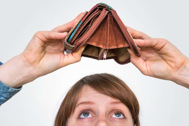 Woman looking into open wallet that has no money in it.