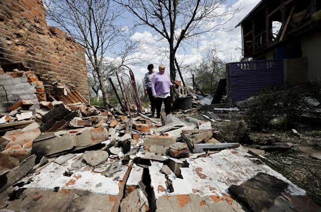 A man and a woman look upon the debris caused by a Russian attack.