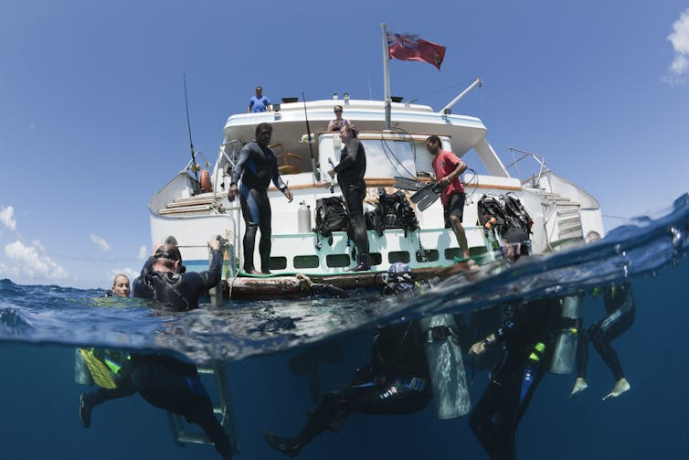 Divers going into the water of a boat with Fijian flag.