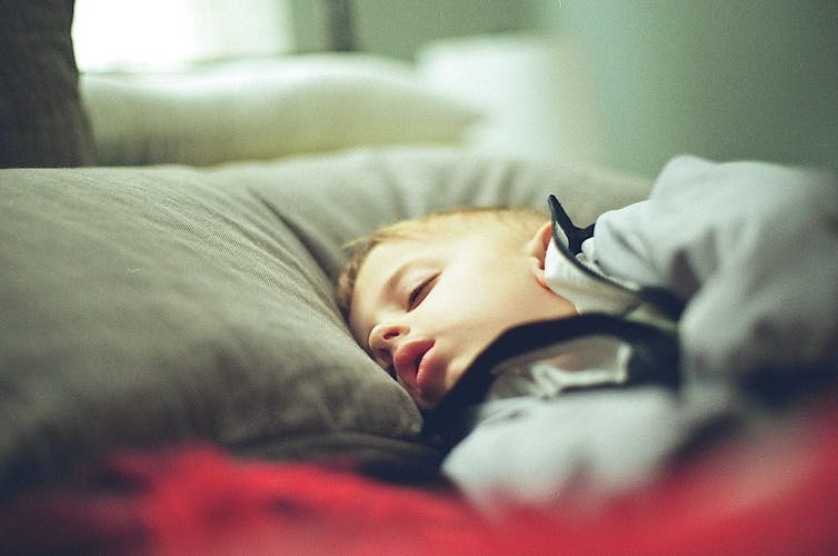 A kid sleeps in bed.