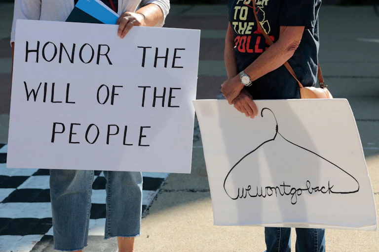 Abortion rights activists hold placards saying 'Honor the Will of the People' and 'We Won't go Back.'