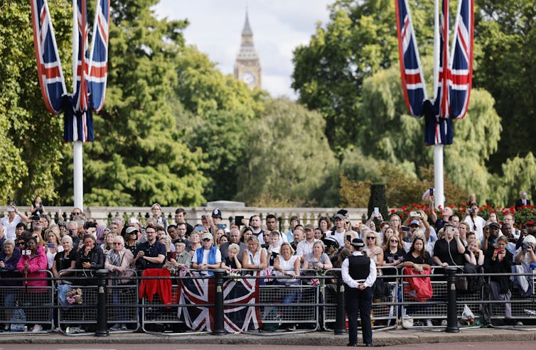 Crowds gather at Buckingham Palace to watch the Queen's casket pass.