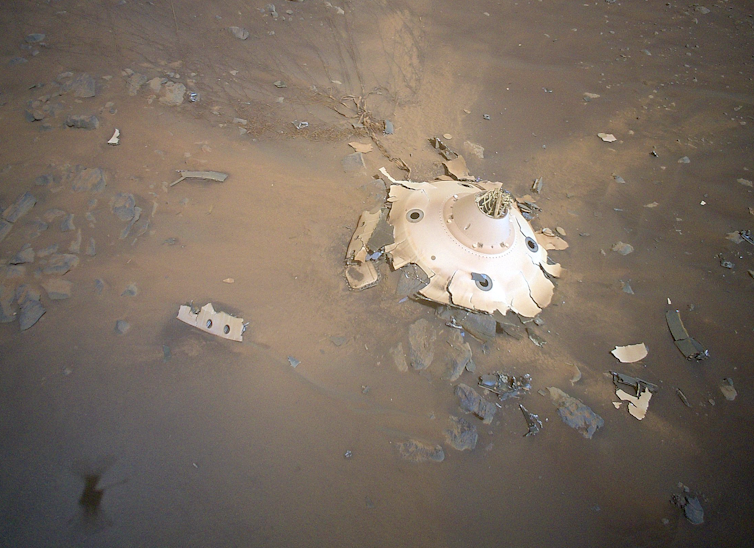 Ein abgeflachtes, rundes, weißes Metallobjekt auf der Marsoberfläche.