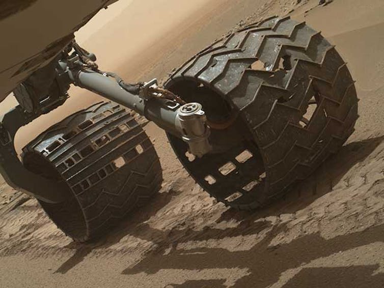 Ein Foto der Räder des Rovers Curiosity mit sichtbaren Löchern.