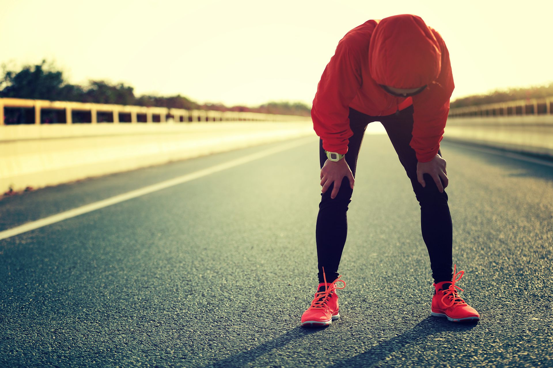 Une sportive appuie ses mains sur ses genoux pour récupérer après un effort intense