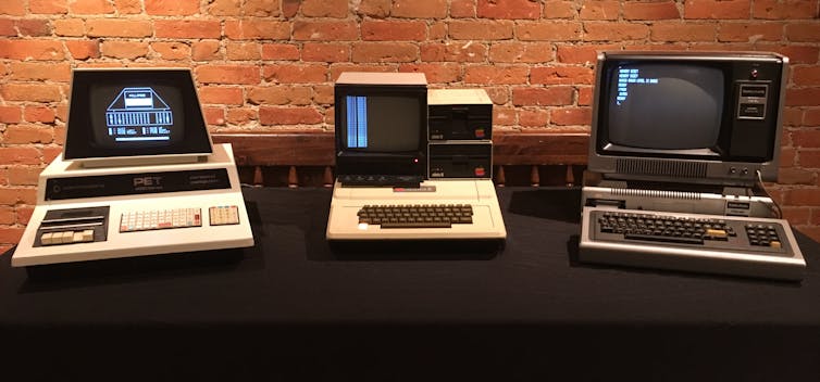 Three old computers sitting on a table.