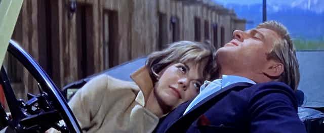 A woman (Natalie Wood) leans on a handsome man (Robert Redford) in a car.