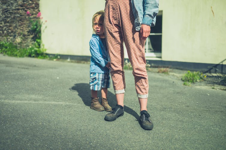 A child clings to their parent.