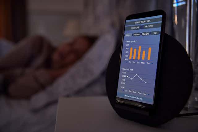 Person in bed and phone screen showing biometric data