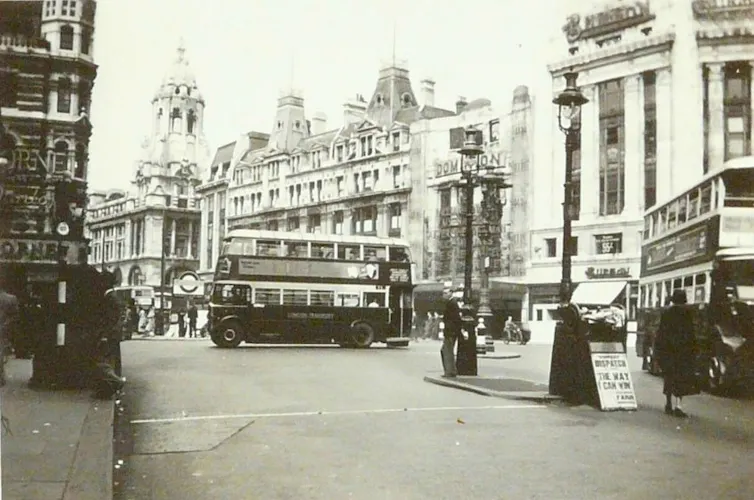 An archival photo of a bus in a city centre, in black and white.
