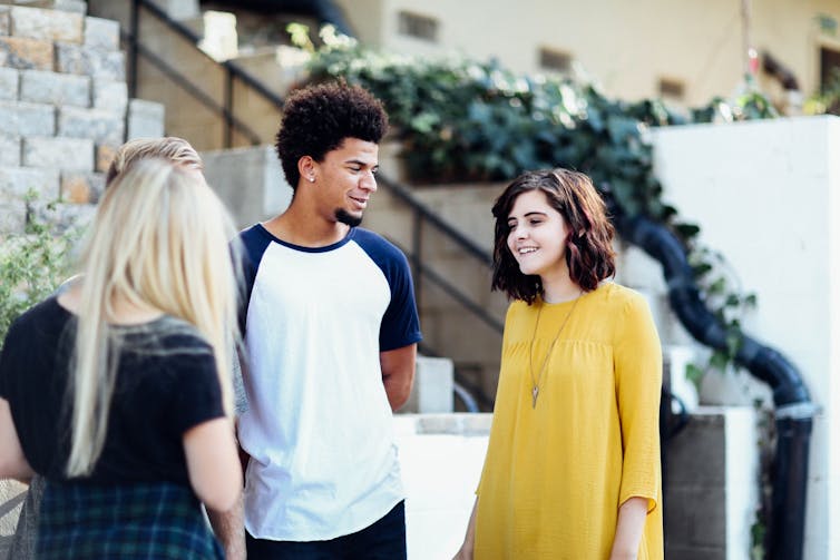 Three teenagers (two female, one male) standing chatting