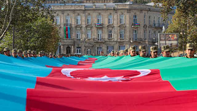 zeri soldiers carry a large-scale national flag on the anniversary of the end of the 2020 war over the Nagorno-Karabakh region between Azerbaijan and Armenia, in downtown Baku, November 2021.