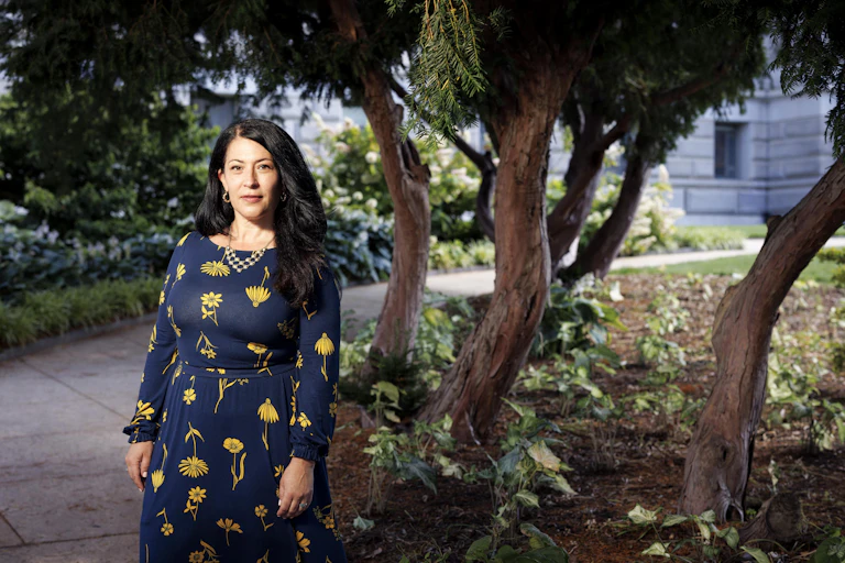 Portrait of Ada Limón standing on a tree-lined walkway