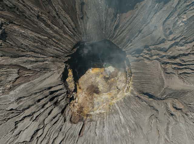 an overhead shot of a volcano crater with smoke