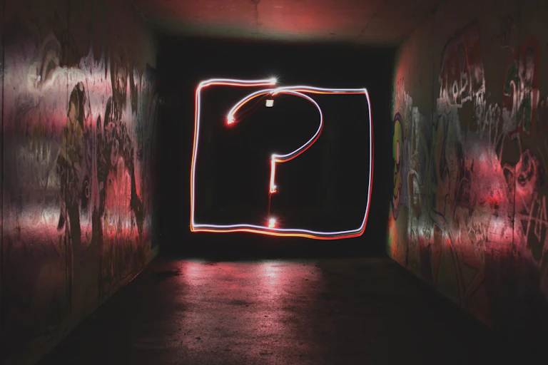 Neon question mark in a dark alley
