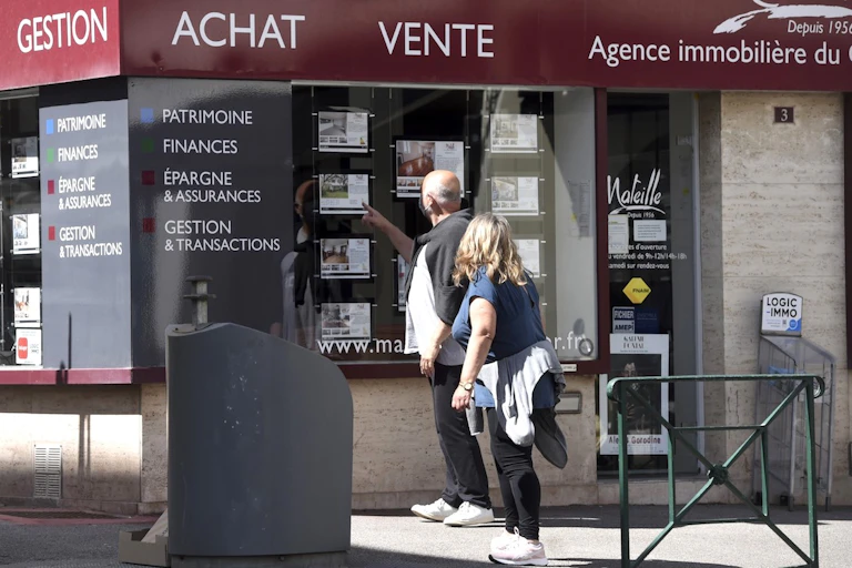 Deux passants devant une agence immobilière.