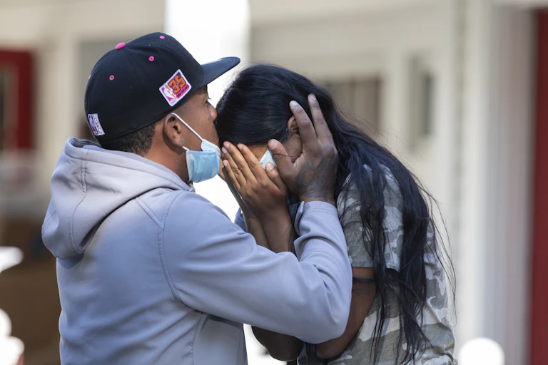 Man holds head of crying woman and kisses her forehead.