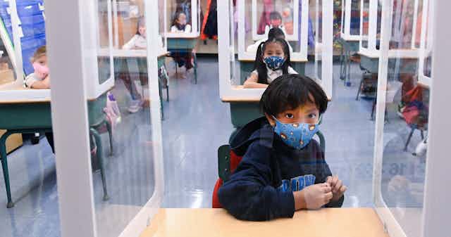 Children seen in a classroom wearing masks.