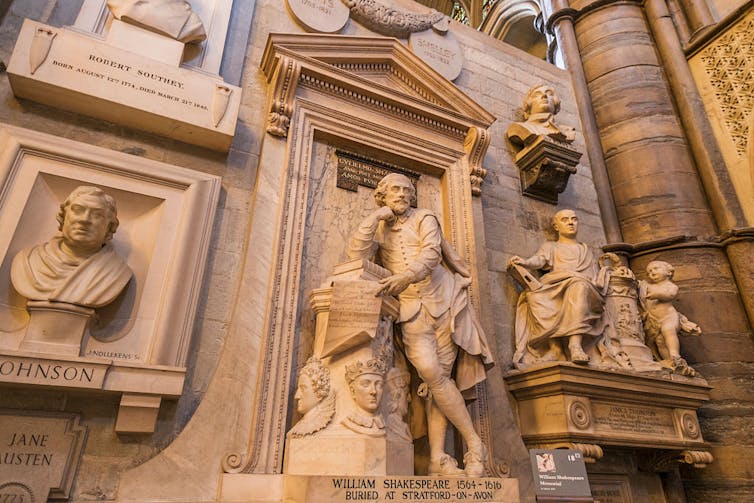 A statue of Shakespeare stands surrounded by other statues and busts of artists.