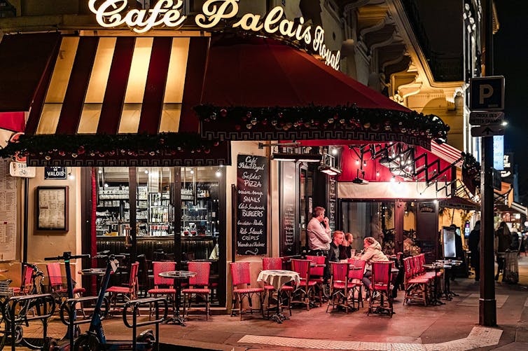 Sillas rojas y mesas en el exterior del café Palais Royal en París.