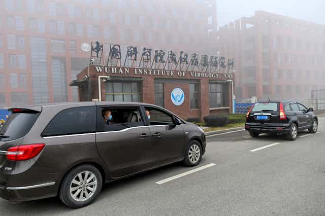 Des voitures officielles sombres s'arrêtent devant le Wuhan Institute of Virology, dans la brume