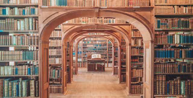 A corridor in a wood paneled library surrounded by books.