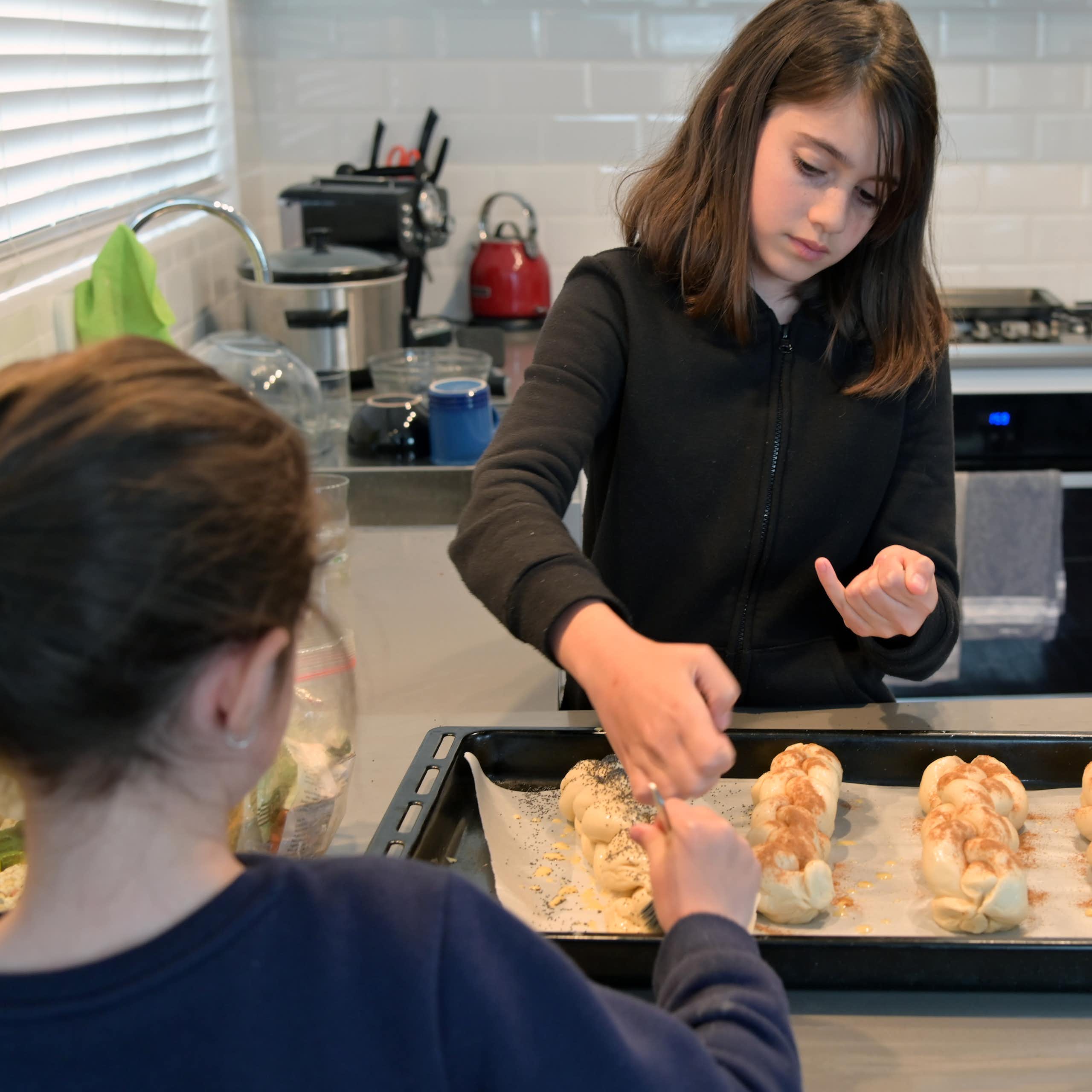 Two young Jewish girls baking challah bread.