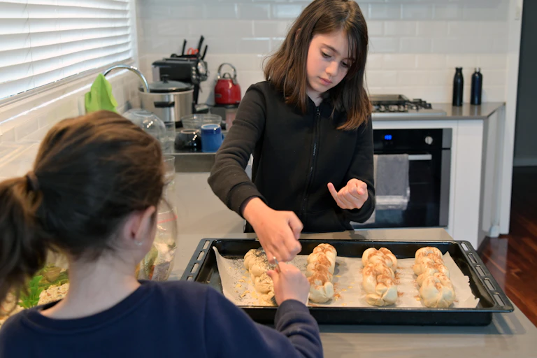 Two young Jewish girls baking challah bread.