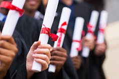 Hands seen holding diplomas.