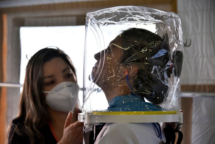 Health care provider tests a ventilation helmet on a patient.
