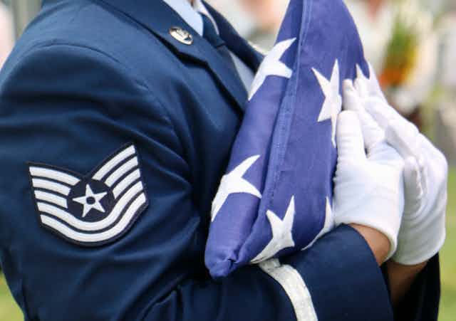 A U.S. Air Force member holds a folded American flag.