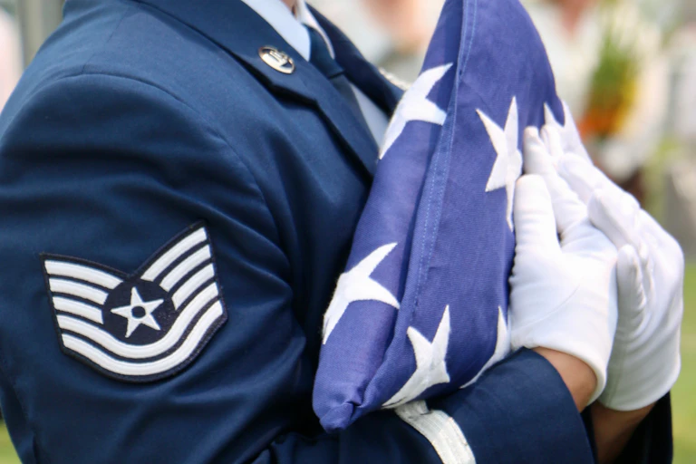 A U.S. Air Force member holds a folded American flag.