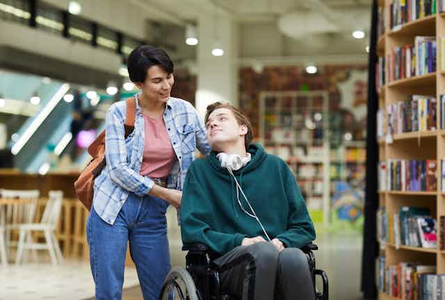 woman helps young man in wheelchair