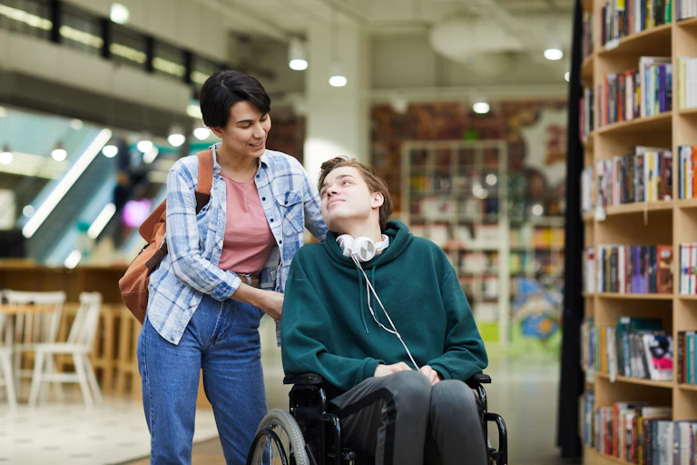 woman helps young man in wheelchair