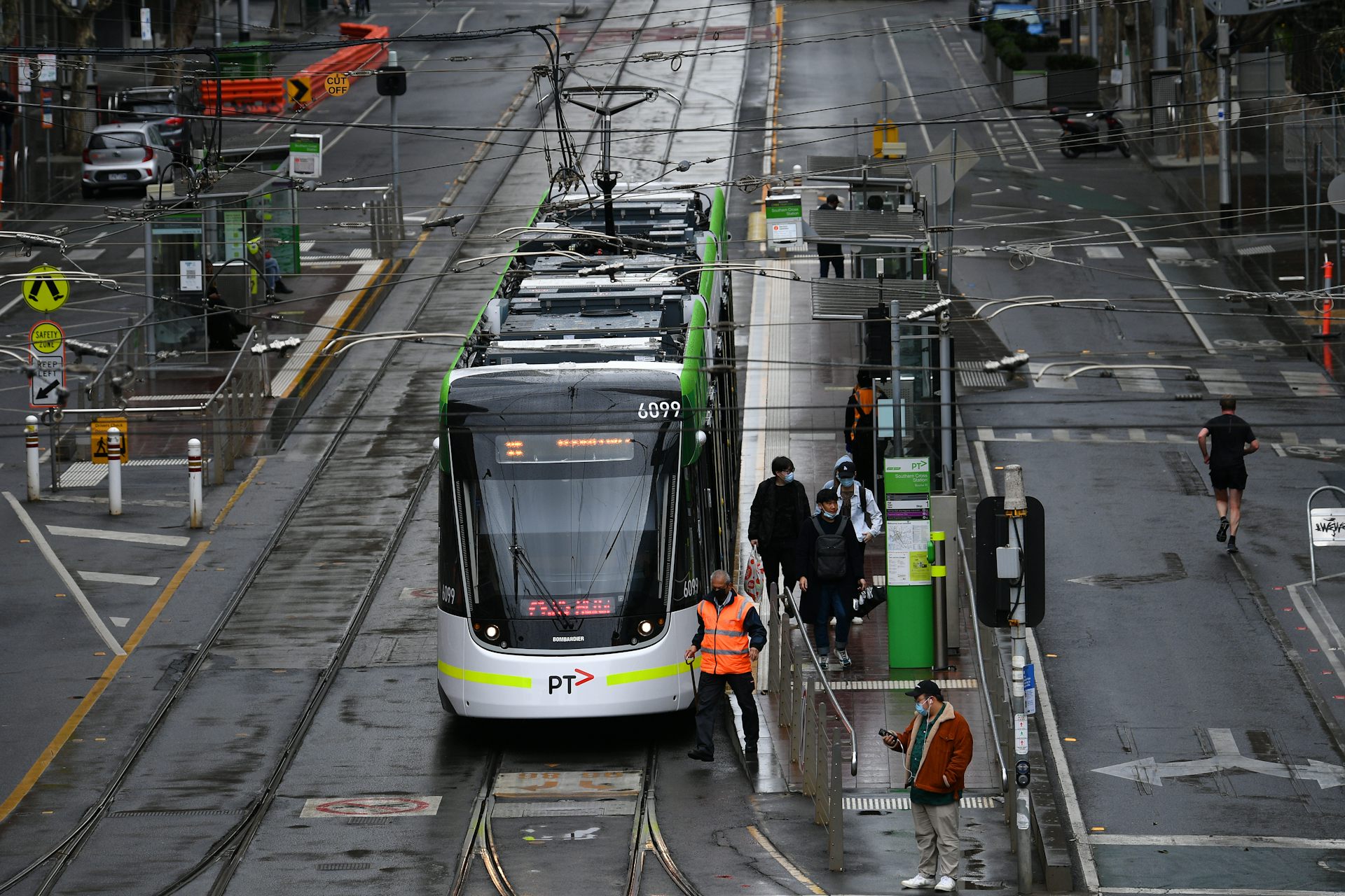 Near-empty city street as a handful of passengers get off a tram