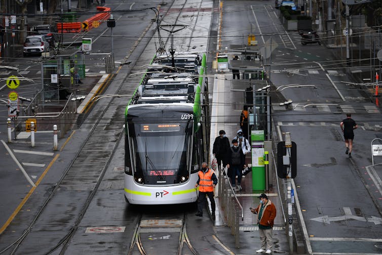 Near-empty city street as a handful of passengers get off a tram