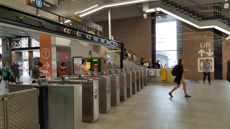 A woman walks through barrier gates at a train station