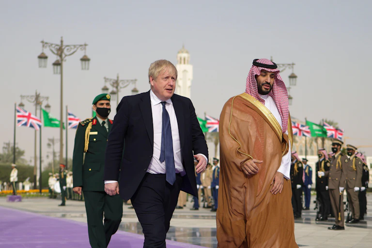 Two men walk down a purple carpet.