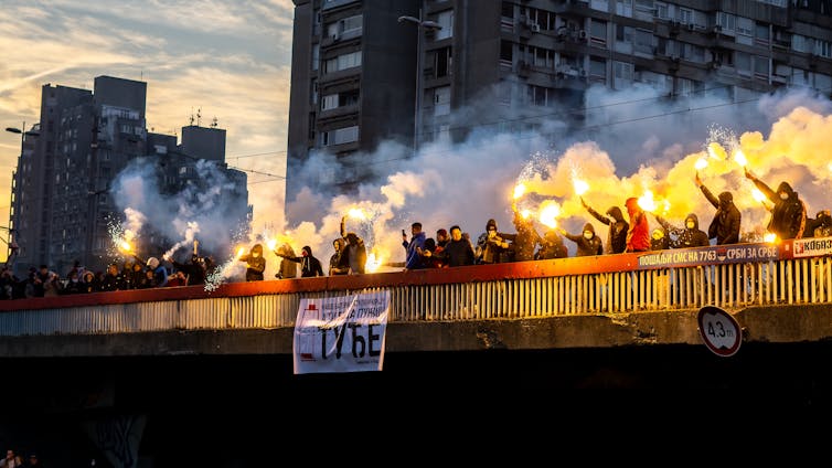 Protesters release flares from a city bridge