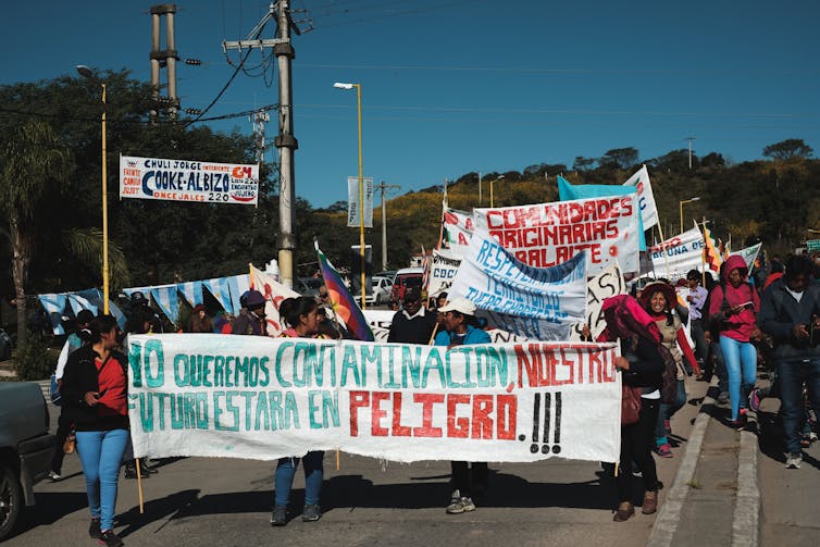 Anti-mine protesters march along a street behind a large banner