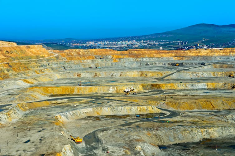 Aerial view across an open copper mine to the town beyond