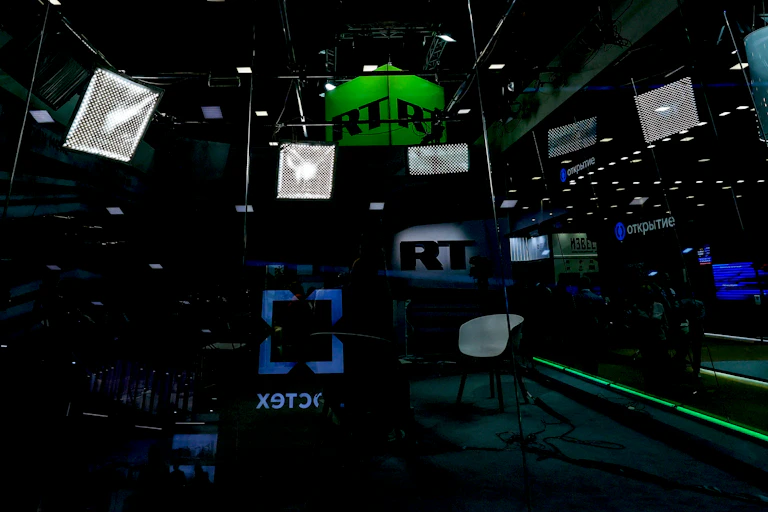 A group of screens and speakers surround an area with chairs and lighting