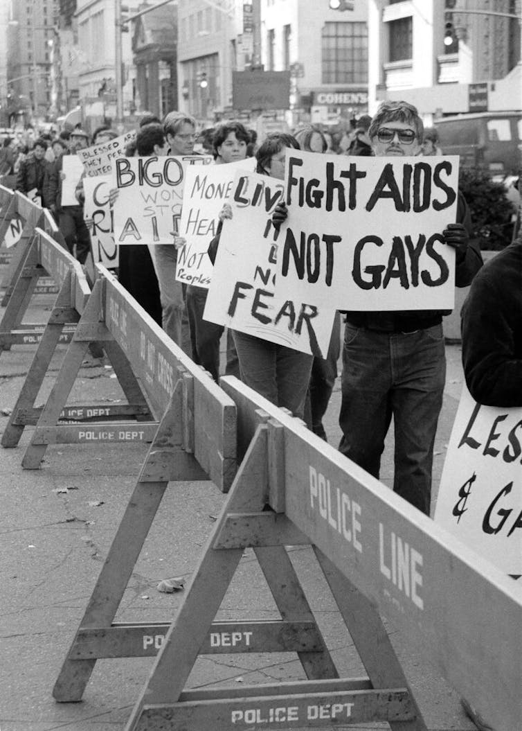 Demonstrators holding signs protesting against AIDS discrimination