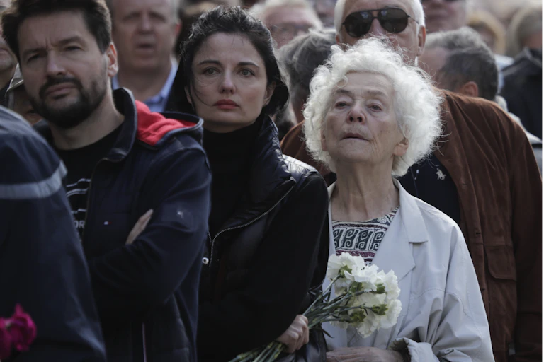 Un groupe d'hommes et de femmes, une tenant des fleurs, debout dans une file