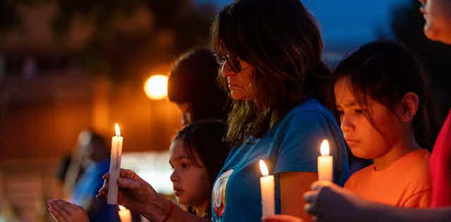 People hold candles during a vigil. 