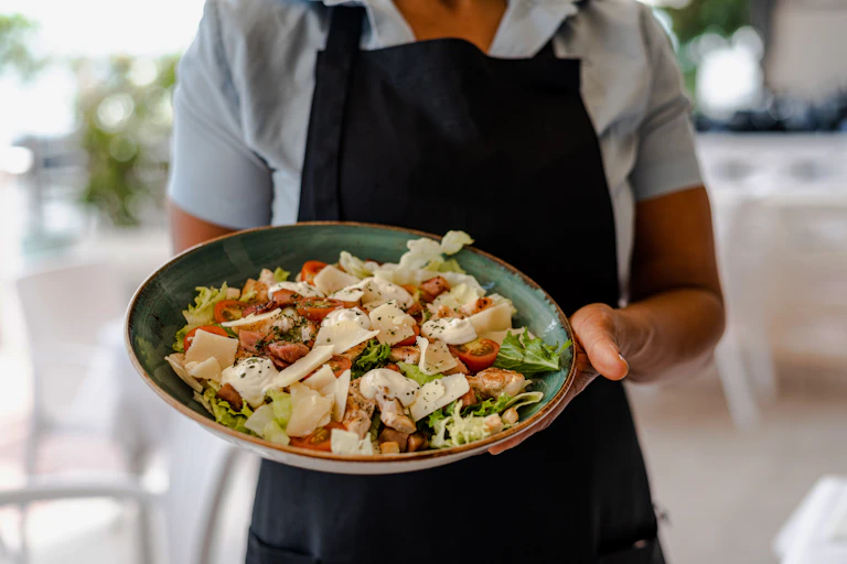 A waiter carries a salad in a cafe.